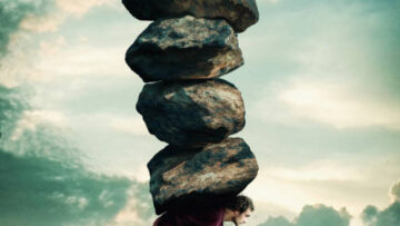 Man carries a stack of heavy rocks.