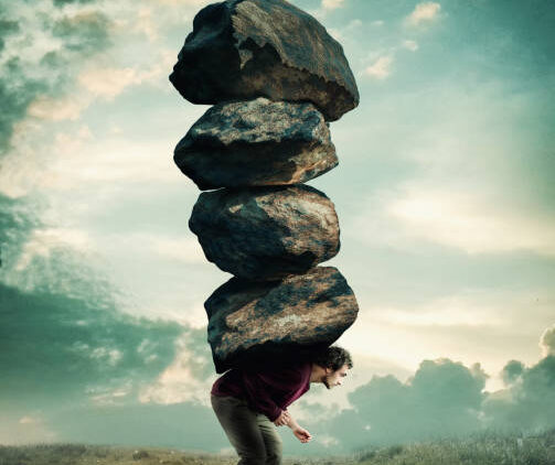 Man carries a stack of heavy rocks.