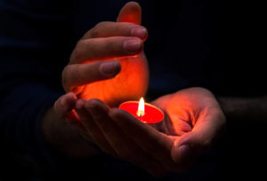 hands protecting candle